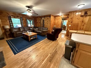 Un interior de madera con un sofá, sillones, una mesa de centro y una zona de comedor.