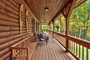 A wooden deck with a table and chairs, surrounded by log walls and a railing. - Peaceful Mountain Escape with Deck and Game Room in Jamaica, Vermont (Jamaica)