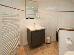 A bathroom with a white sink, a mirror, a toilet, and a washing machine. - Schmalstieg 11a, Wyker Perle (Wyk auf Foehr)