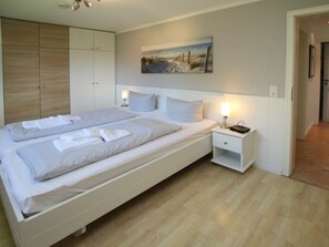 A bedroom with a double bed, bedside tables, a wardrobe, and a painting on the wall. - Schmalstieg 11a, Wyker Perle (Wyk auf Foehr)