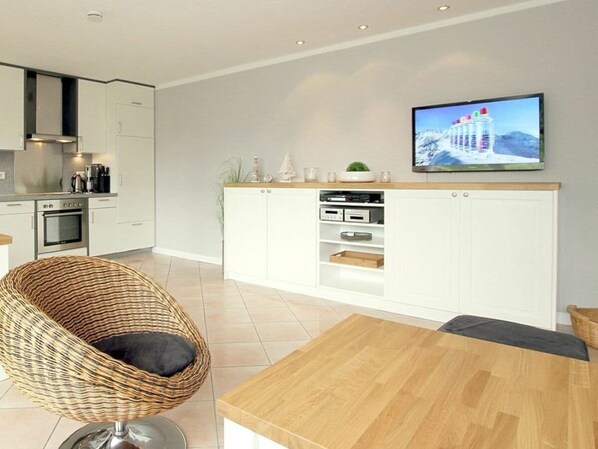 Een moderne keuken met witte kasten, een inbouwoven en een flatscreen televisie boven de kasten.