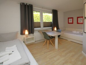 A compact room with a bed, a small table with chairs, a sofa, and a window with curtains. - Schmalstieg 11a, Wyker Perle (Wyk auf Foehr)