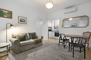 Ein Wohnzimmer mit einem gestreiften Sofa, einem Esstisch mit Stühlen, einer Lampe und einem großen Spiegel.
