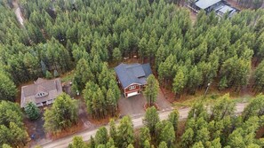 Ein Wohngebiet mit einem Haus, umgeben von dichtem Wald, einer gepflasterten Auffahrt und einer sichtbaren Garage.