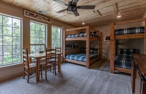 A cabin interior with bunk beds, a dining table, chairs, and a ceiling fan. - Secluded Cabin with Scenic Reservoir Access & Trails in Island Park, Idaho (Island Park)
