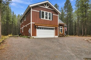 A two-story wooden house with a garage, surrounded by a forest. - Secluded Cabin with Scenic Reservoir Access & Trails in Island Park, Idaho (Island Park)