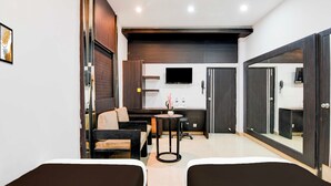 A hotel room with two beds, a small table with a vase, a sofa, a TV, and a wardrobe. - Townhouse Kolkata Northern Park (Kolkata)