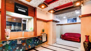 A reception area with a 'Townhouse' sign, a reception desk, a red sofa, and a vase. - Townhouse Kolkata Northern Park (Kolkata)