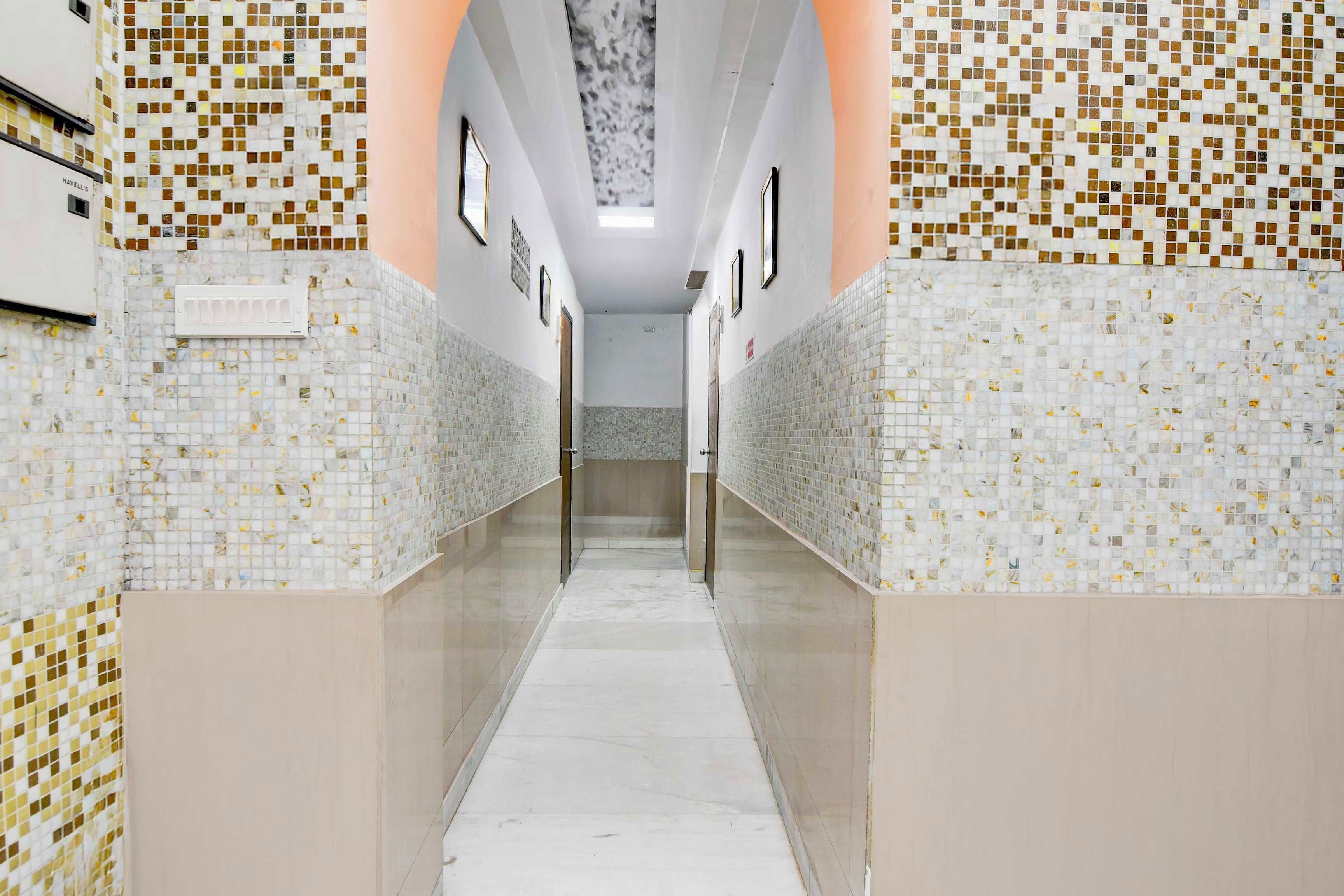 Un pasillo con paredes de azulejos y suelo de mármol, que conduce a una puerta al final.