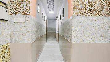 Un pasillo con paredes de azulejos y suelo de mármol, que conduce a una puerta al final.