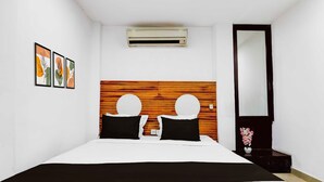A hotel room with a bed, a wooden headboard, a mirror, and framed artwork on the wall. - Townhouse Kolkata Northern Park (Kolkata)