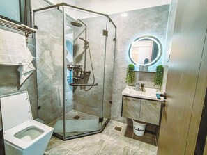 Ein Badezimmer mit Duschkabine, Waschbecken mit Spiegel und Toilette.