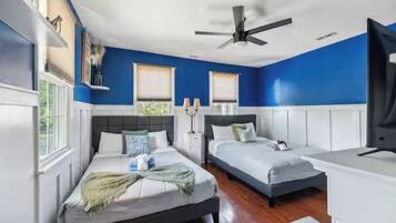 Une chambre avec deux lits, un ventilateur de plafond et une fenêtre donnant sur un beau paysage.