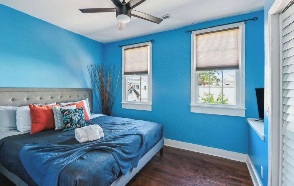 A bedroom with a bed, two windows, a ceiling fan, and a nightstand.