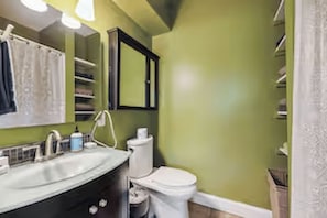 Ein Badezimmer mit Waschbecken, Spiegel, Toilette und Stauraumschrank.