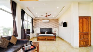 A modern living room with a sofa, a coffee table, a bed with a headboard, and a wooden door. - Townhouse Kolkata Padmapukur Lake (Kolkata)