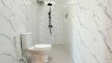 Un baño con inodoro, ducha y pared de mármol.