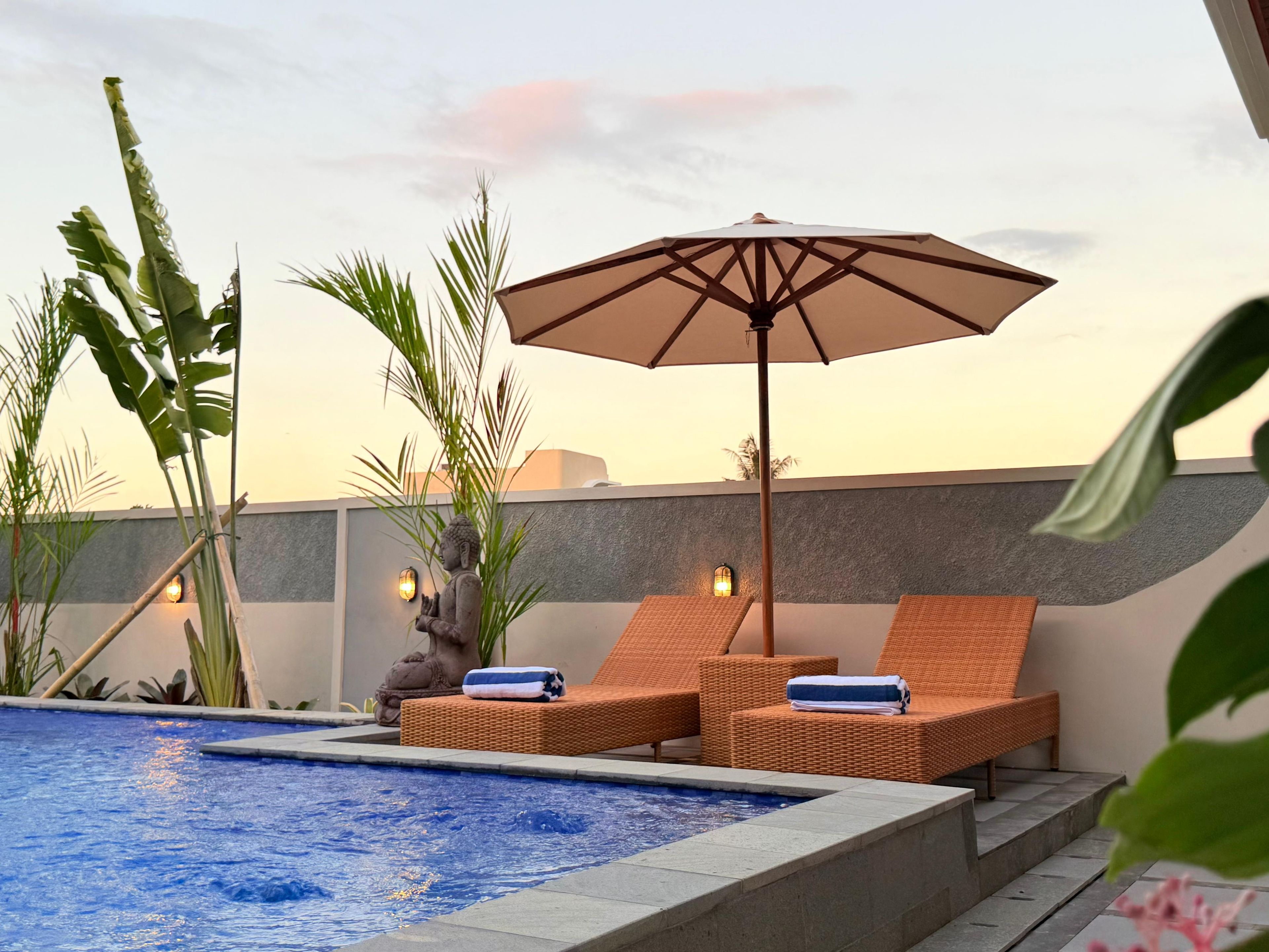 A rooftop pool area with lounge chairs and an umbrella.