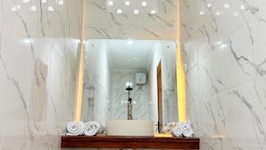 Une salle de bain avec un mur en marbre, un lavabo avec un miroir et des serviettes.