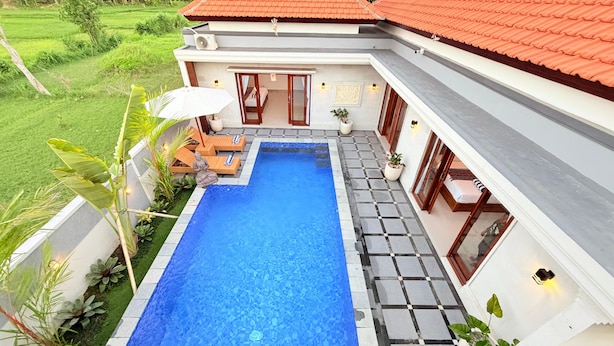 Une maison moderne avec une piscine, un toit recouvert de tuiles rouges et un jardin.