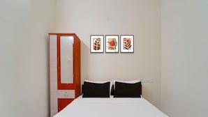 A bedroom with a bed, two pillows, a wardrobe, and three framed artworks on the wall. - Townhouse Coimbatore Peelamedu (Coimbatore)