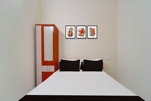 Un dormitorio con una cama, dos almohadas, un armario y tres cuadros en la pared.