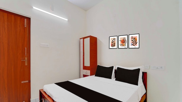 A bedroom with a bed, a wardrobe, and three framed pictures on the wall. - Townhouse Coimbatore Peelamedu (Coimbatore)