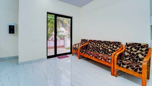 A spacious room with a marble floor, a sofa set, a sliding glass door leading outside, and a wall-mounted electrical outlet. - Townhouse Coimbatore Peelamedu (Coimbatore)