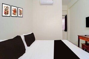Habitación de hotel con cama, escritorio, televisor y tres cuadros en la pared.