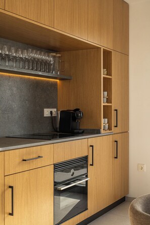 A modern kitchen with wooden cabinets, a built-in oven, a coffee maker, and a wine rack. - Villa Daya - private pool - ocean view - 8 guests - 4 bedrooms - 3 bathrooms (Salobrena)