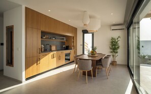 A modern kitchen with wooden cabinets, a dining area with a table and chairs, and a large window providing a view outside. - Villa Daya - private pool - ocean view - 8 guests - 4 bedrooms - 3 bathrooms (Salobrena)