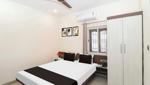 A bedroom with a bed, a nightstand, a window with bars, a wardrobe, and a ceiling fan. - Townhouse Birsa Railway Stadium Ranchi (Ranchi)