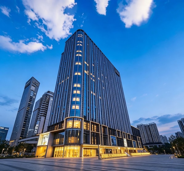 A modern high-rise building with a prominent glass facade, surrounded by other tall structures. - Yufei Smart City View Residence (Guangzhou)
