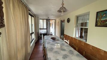 A dining area with a long table, chairs, a ceiling fan, and a window with curtains.