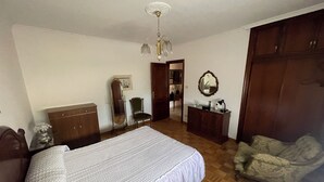 Ein Schlafzimmer mit Bett, Kommode, Stuhl und Spiegel.