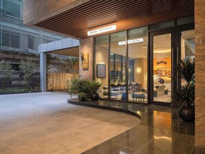 A modern building with a sign reading 'LOCAL' and 'GOOD DAYS START HERE!' The entrance has glass doors and a seating area with chairs and tables inside. - The Nelson Luxury 3BR Apartment in Lang Ha street – Free Pool, Gym & Sauna (Hà Nội)