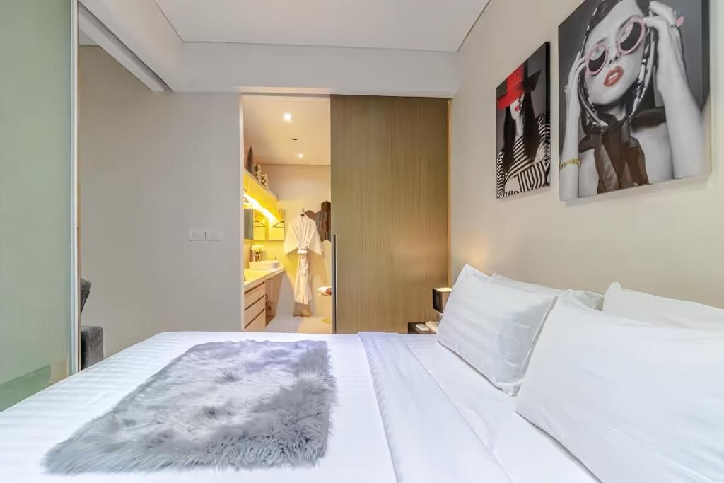 A hotel room with a bed, a fluffy rug, and a bathroom visible through an open door.