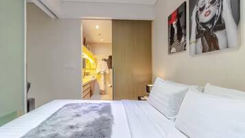 A hotel room with a bed, a fluffy rug, and a bathroom visible through an open door.
