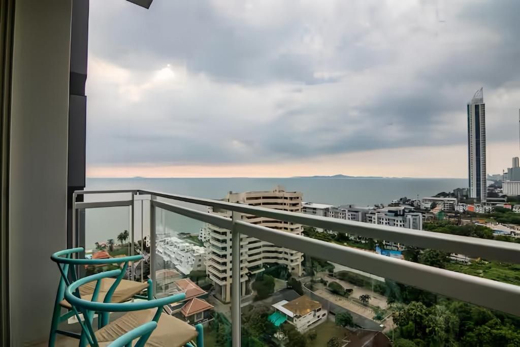 A balcony with a view of a cityscape, including buildings and a body of water.