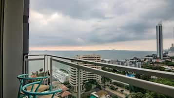 A balcony with a view of a cityscape, including buildings and a body of water.