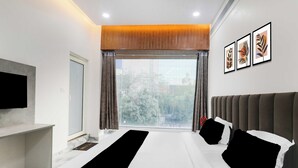 A modern hotel room with a large bed, a flat-screen TV, a window with curtains, and framed artwork on the wall. - Townhouse Lucknow Emerald Mall (Lucknow)