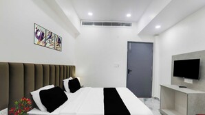 A modern hotel room with a bed, bedside table, TV, and artwork on the wall. - Townhouse Lucknow Emerald Mall (Lucknow)