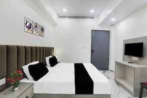 Ein modernes Hotelzimmer mit Bett, Nachttisch, Fernseher und Kunstwerk an der Wand.