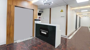 A reception area with a reception desk, a fire extinguisher, a warning sign, and a reception sign. - Townhouse Lucknow Emerald Mall (Lucknow)