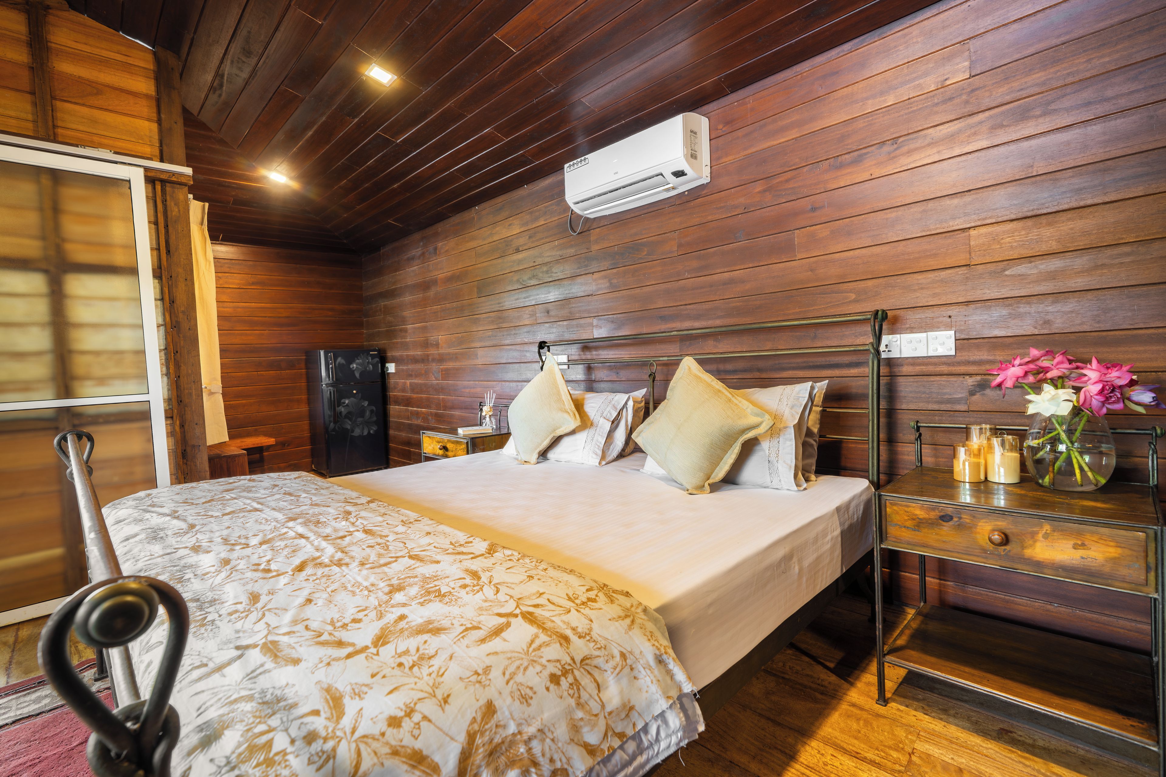 Een kamer met houten lambrisering, een bed, nachtkastje en een airconditioning.
