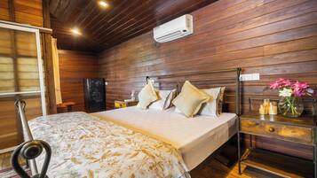 Een kamer met houten lambrisering, een bed, nachtkastje en een airconditioning.