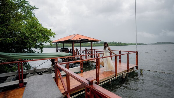 Une jetée en bois s’étendant sur une étendue d’eau, avec un espace de repos abrité et une table.