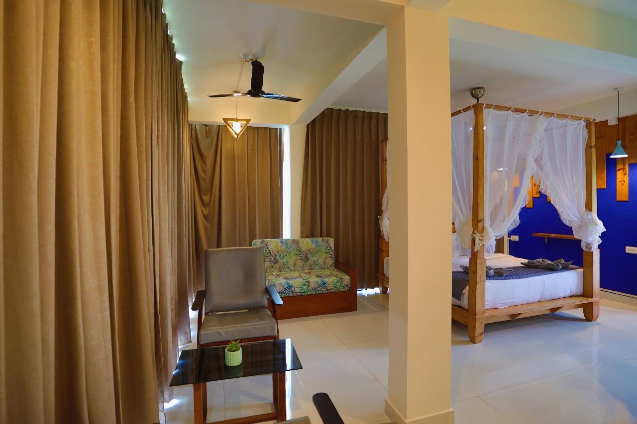 A room with a bed, a chair, a table, and a ceiling fan.