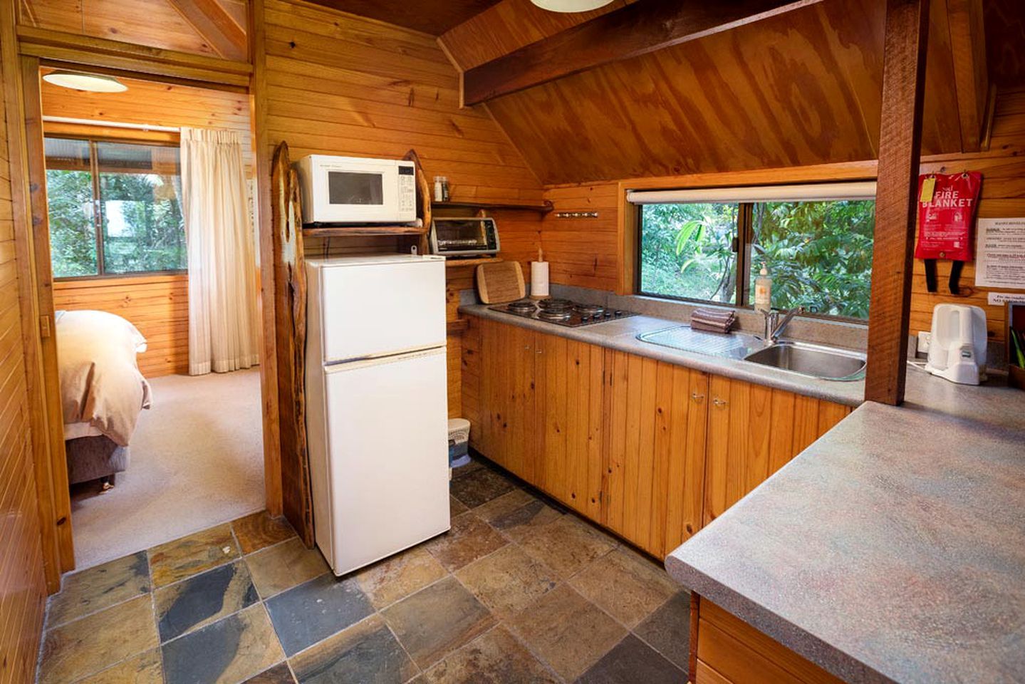 A compact kitchen with a refrigerator, microwave, and stove.
