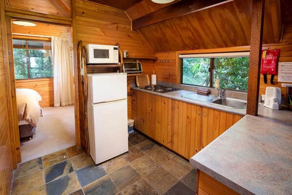 A compact kitchen with a refrigerator, microwave, and stove.